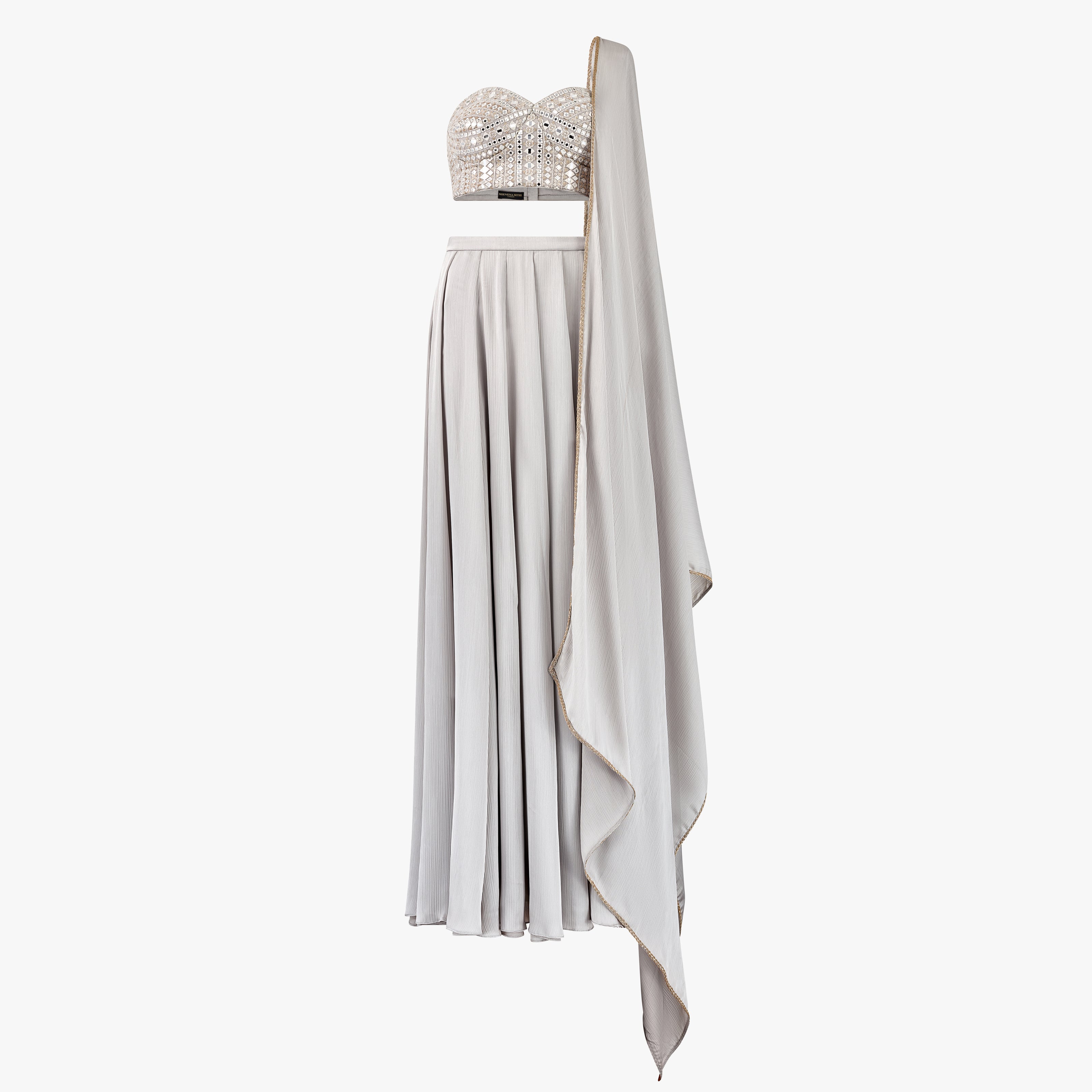 The Carlia lehenga set features a delicate mirror and chikan kari embellished bandeau top, Paired with a luxurious satin lehenga and matching dupatta, designed by Shenena Sethi