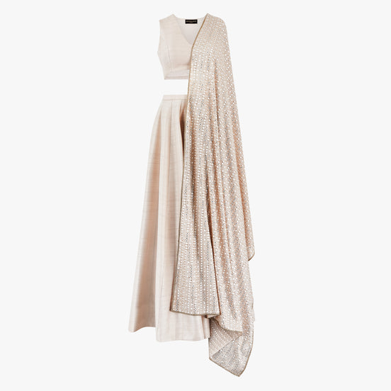 A cream semi raw silk lehenga with a crop top and a mirror dupatta. Designed by Shenena Sethi