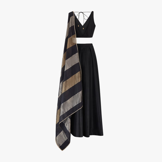 A traditional Indian semi raw silk lehenga and top paired with a chanderi tissue block dupatta in black, silver, and gold colours, designed by Shenena Sethi