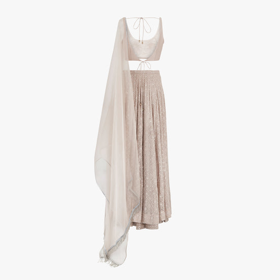 A nude pink chikan kari lehenga, semi raw silk top, accompanied by a soft pure organza dupatta with tassels on the ends, designed by Shenena Sethi